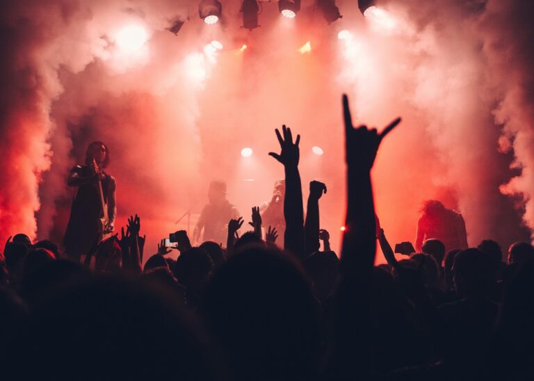 Imagem de mãos fazendo chifre em um público de show de rock.