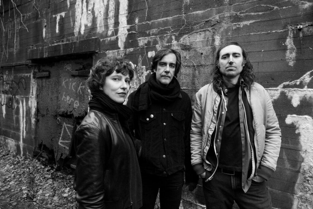 Imagem em preto e branco com os três integrantes da banda A Place to Bury Strangers