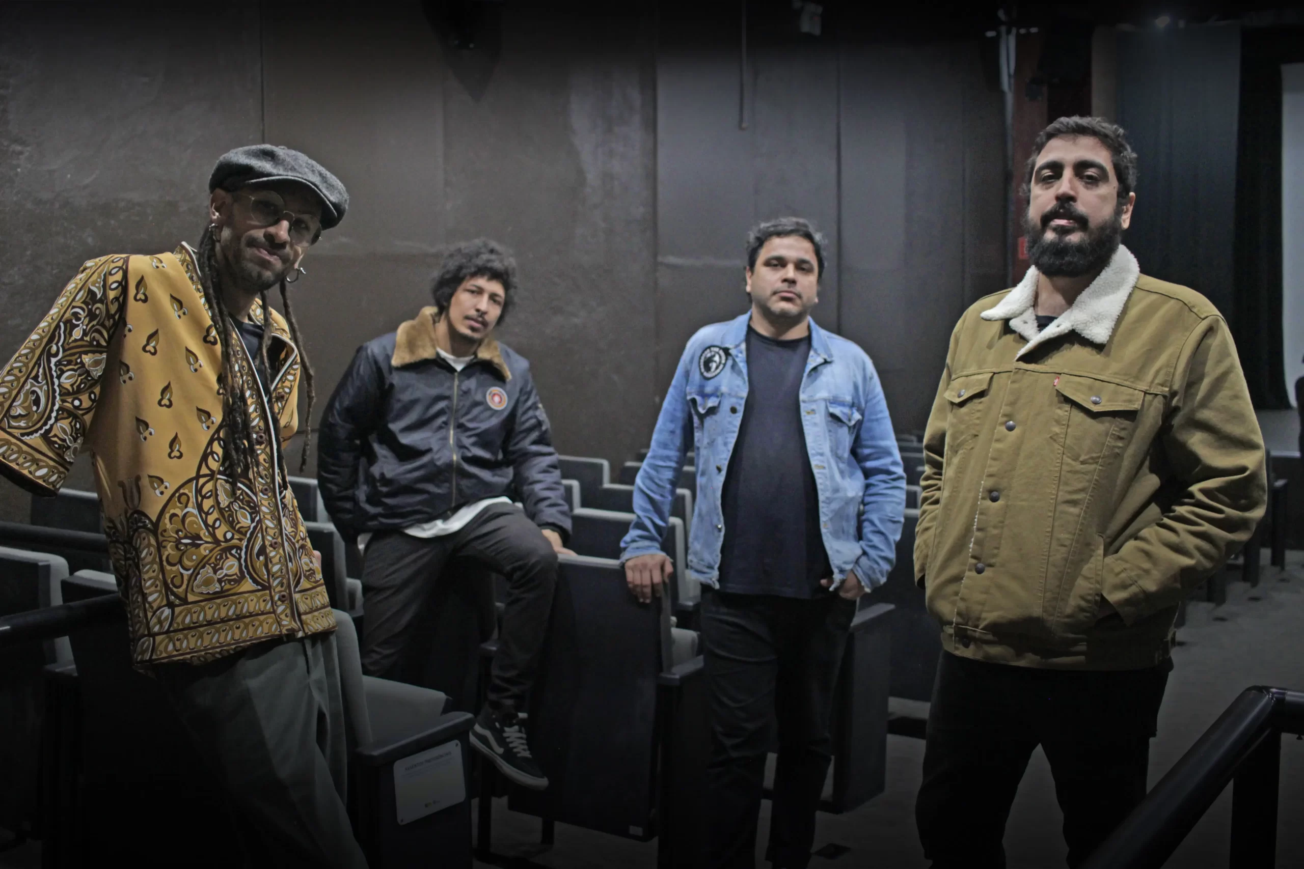 Imagem com os quatro integrantes da banda Bike em uma parede preta