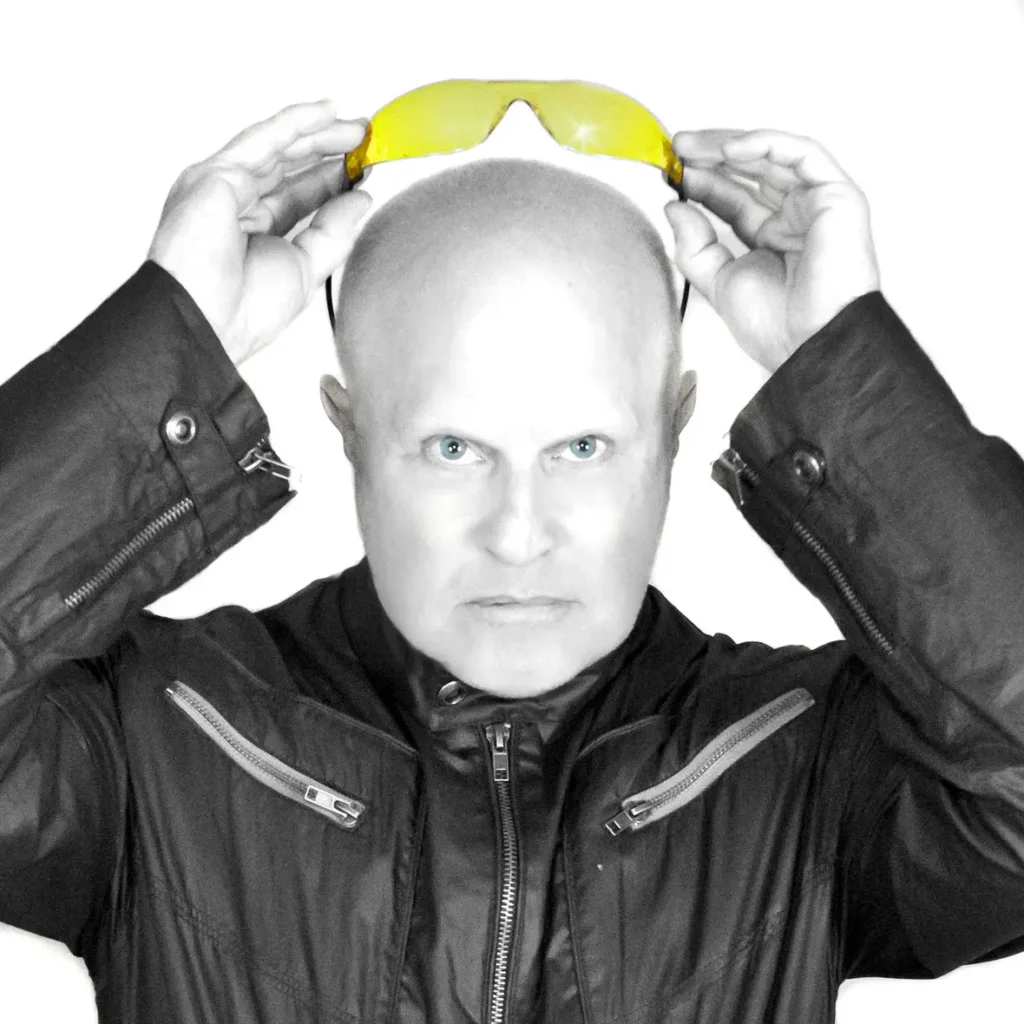 Imagem do vocalista da banda A Flock of Seagulls em preto e branco segurando um óculos amarelo